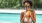 woman stands in pool drinking iced tea
